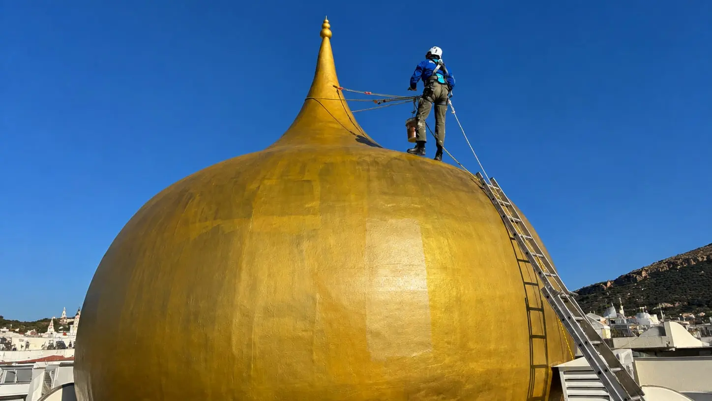 Técnico de Quarzo trabajando desde cuerda sobre la cúpula dorada de un edificio
