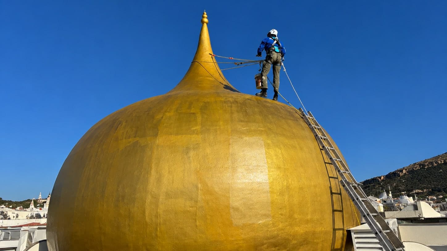 Técnico de Quarzo trabajando desde cuerda sobre la cúpula dorada de un edificio