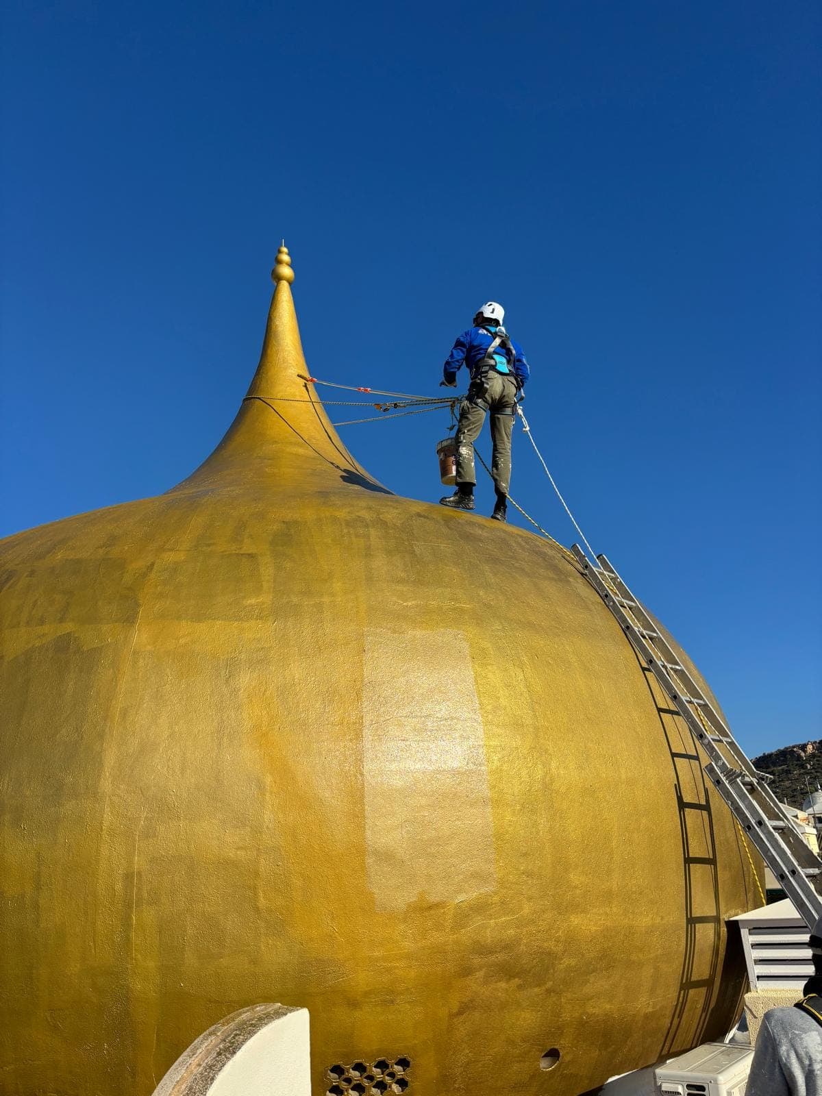Técnico de Quarzo trabajando desde cuerda sobre una cúpula dorada