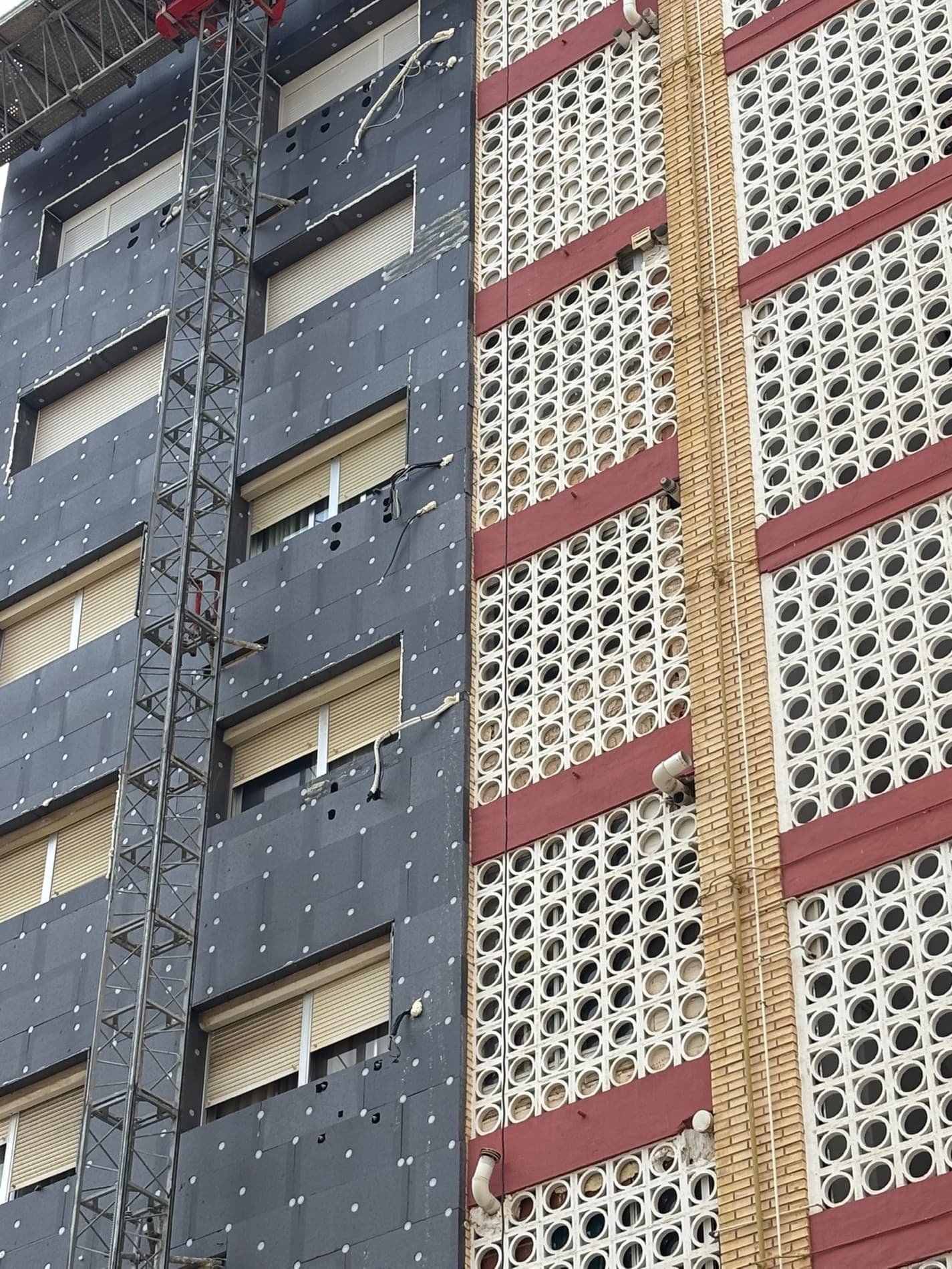 Paneles de aislamiento térmico colocados sobre la fachada, junto a las celosías originales