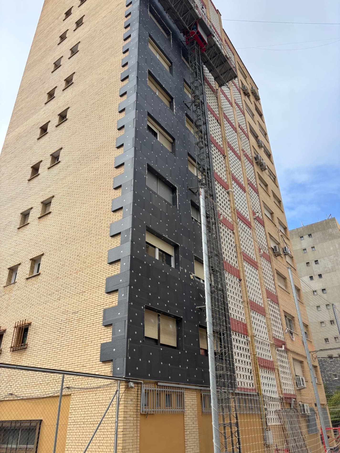 Edificio a media intervención: media fachada con el ladrillo original y media con el aislamiento colocado